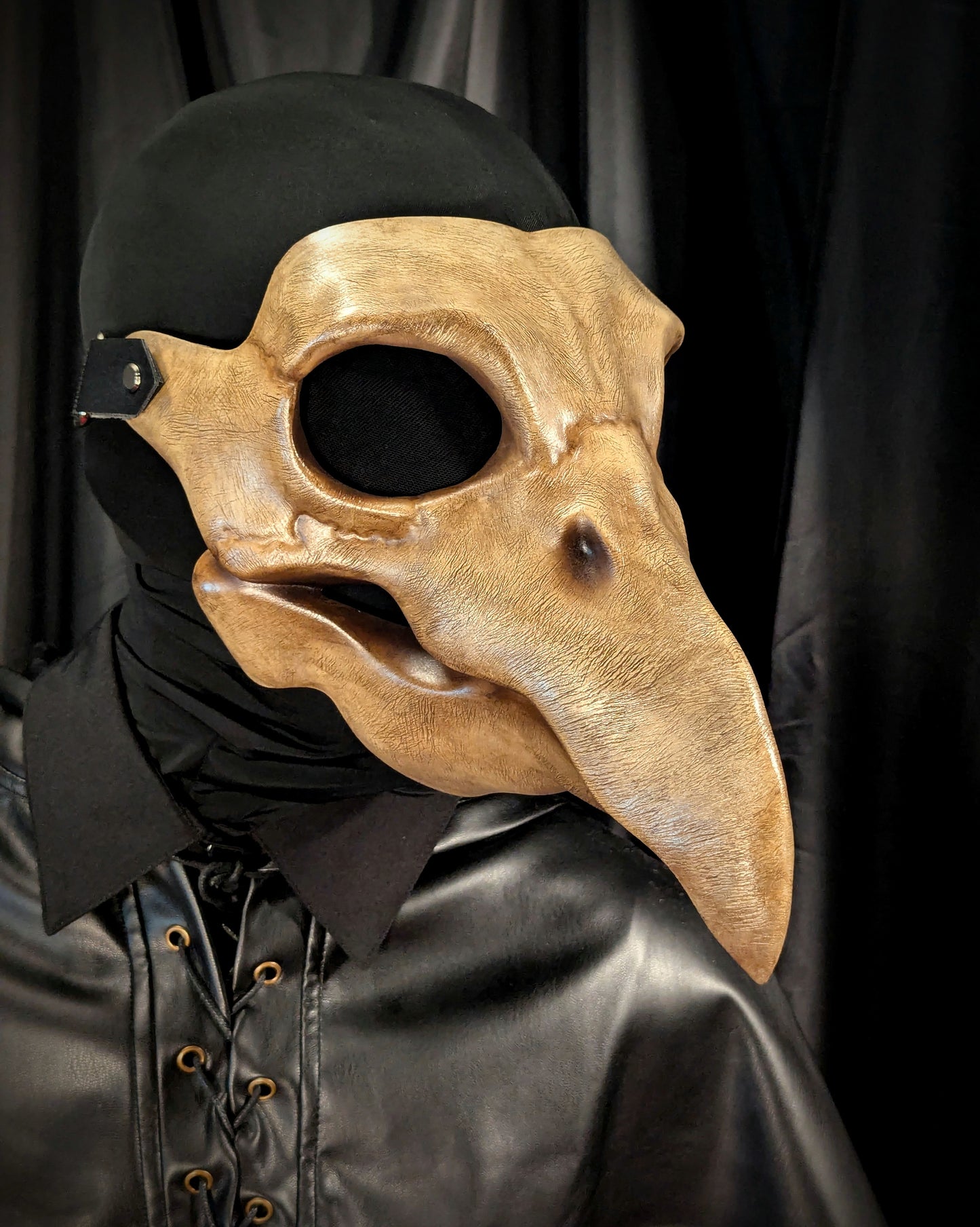 Plague doctor mask with long beak and black clothing on a dark background