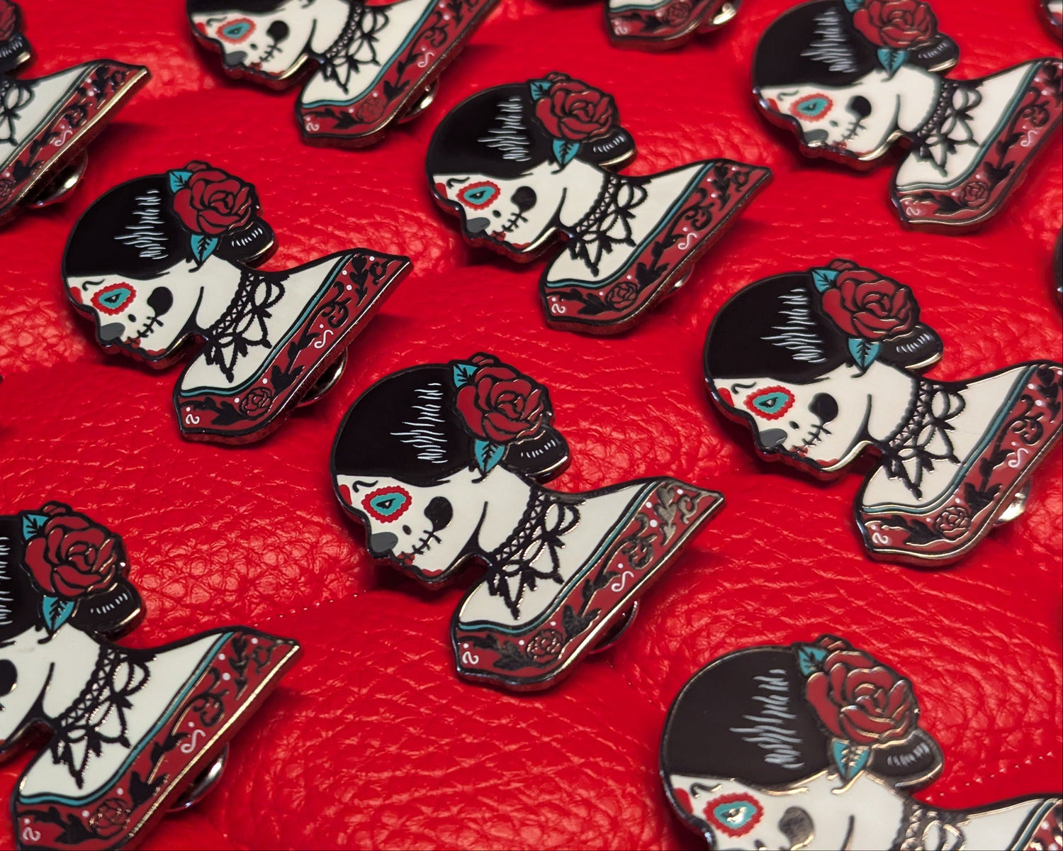 Decorative pins with skull and rose designs on a red background