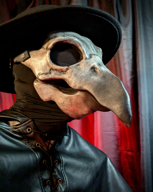Side view of a person wearing a plague doctor mask with a long beak and black hat against a glowing red curtain background.