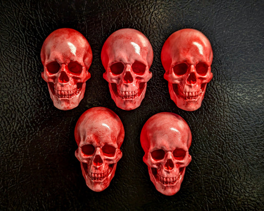 Five miniature pink skulls covered with a bright bloody red color