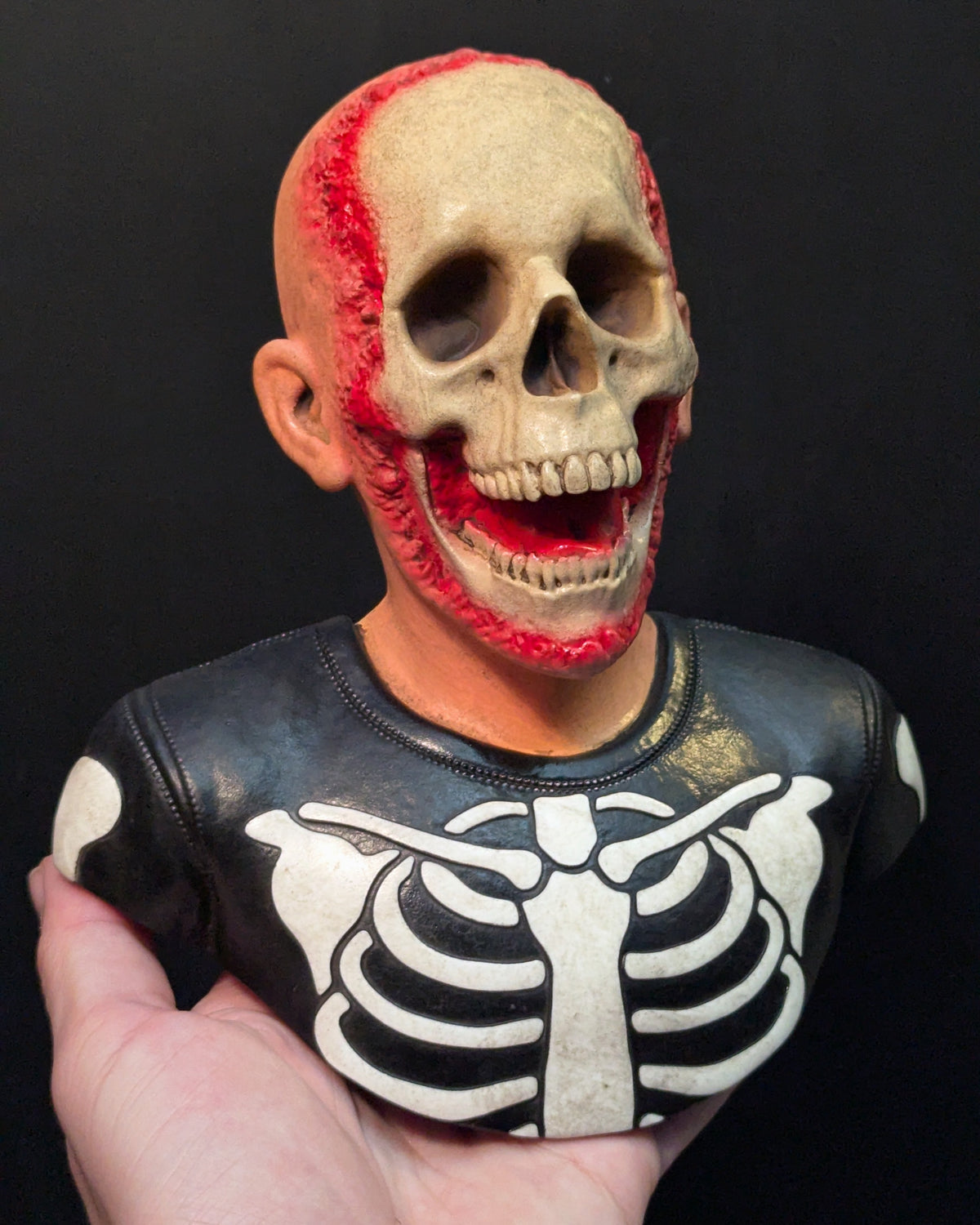 A resin sculpture of a skeleton trick or treater being held in one hand.