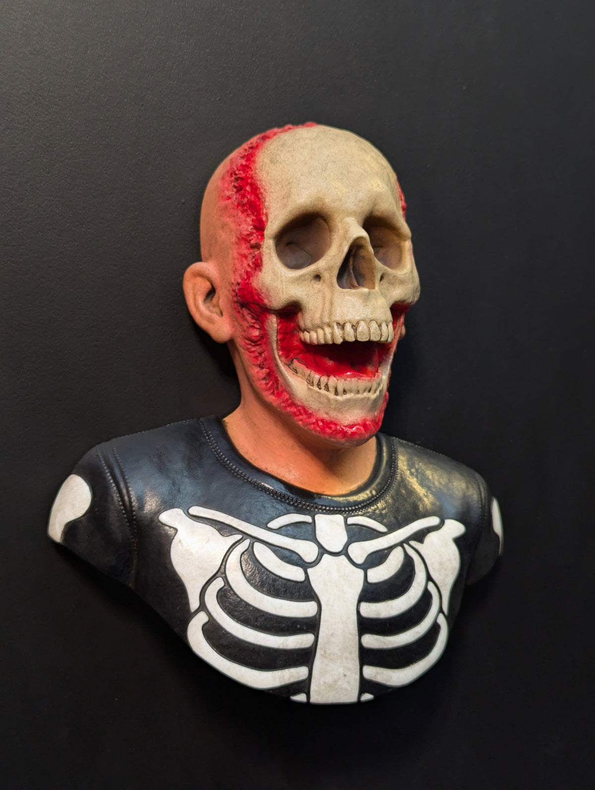 a skeleton trick or treater bust mounted to a black wall